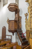 Chaire à prêcher. Notamment en raison de son type de décor, la chaire pourrait dater du 17e siècle ; plus précisément, la reconstruction de l'église étant achevée en 1683, elle est nécessairement postérieure à cette date. Elle pourrait être également contemporaine des stalles du choeur. Chaire à prêcher adossée, accessible par un escalier à volée tournante avec garde-corps métallique. Cuve octogonale sur culot galbé, fermée par un battant. Le dorsal cantonné d'ailerons est surmonté d'un abat-voix également octogonal qui porte un couronnement ajouré à petits balustres tournés. Pointes de diamant sur les panneaux de la cuve et du dorsal, volutes sur les ailerons de ce dernier et pilastres sur ses montants.