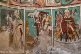 Auron. Chapelle Saint Erige dite d'Ariez <br> Bénédiction de saint Domnin, premier évêque de Digne, disciple de saint Denis. Un bourreau retourne saint Denis sur le gril en présence de deux personnages qui commentent la scène. Le saint et ses diacres enfermés dans une enceinte crénelée sont exposés aux bêtes sauvages -lion, loup et même un cerf! L’un des diacres, à droite, mains jointes lève les yeux vers le ciel, l’autre, revêtu d’une dalmatique, fait un geste de crainte. Le saint, un livre à la main gauche, bénit de l’autre main. Tous trois ont revêtu leur tenue liturgique.