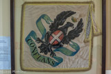 <center>Conflans : Musée d’Art et d’Histoire.</center> Fanions aux armes de Conflans et l'Hôpital, peints, bordés de franges dorées avec galon jaune. Sur une face, sur fond blanc, en diagonale, un aigle noir portant sur son corps le drapeau de la Savoie (croix blanche sur fond rouge). Ces fanions sont probablement des copies de ceux réalisés pour la cérémonie de la pose de la première pierre de l'endiguement de l'Isère en 1824, en présence du roi Charles-Félix, d'où les lettres C.F. entrelacées au dos de ces fanions. Perché sur son éperon rocheux, Conflans domine la confluence de l’Isère et de l'Arly, d'où son nom. Dès le Moyen-Age, la cité qui contrôle l'accès à la Tarentaise connaît une longue période de prospérité. Conflans va jouer un rôle de centre pour le commerce régional recevant, encore au XVIIIe siècle, jusqu'à 1500 personnes sur sa grande place où prospèrent bourgeois et commerçants. La Maison Rouge ou les fontaines en pierre taillée témoignent toujours de cette richesse passée.