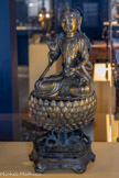 <center>Guanyin</center>Chine
Fin dynastie Yuan (1279-1368) - début dynastie Ming (1368- 1644)?
Bronze doré.
Introduit en Chine au IIIe siècle, le culte de Guanyin se diffuse rapidement. Sous les dynasties Song (960-1279) et Yuan, la divinité se féminise. La présente statue conserve son aspect masculin originel.
Assise en padmasâna sur un siège de diamant lotiforme surélevé, la divinité tient dans la main gauche un vase (.kalasha) et de l’autre tenait vraisemblablement une fleur de lotus. Le buste est étroit, souligné par le nœud du dhoti. Le vêtement ouvragé évoque l’art tibétain. Le diadème, que se réapproprient les taoïstes au XVIe siècle, renvoie à la sculpture bouddhique chinoise postérieure à la dynastie Tang (618-907).