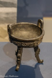 <center></center>Vase ding. Chine. Dynastie Qing (1644-1911). Bronze. Ce vase tripode, à pieds annulaires, d’époque récente, renvoie à une forme ancienne, attestée sous la dynastie des Shang (XIVe-XIIe siècles av. J.-C.). Ce modèle archaïsant est référencé dans le Xiqing gu jian (Miroir des Antiquités du Pavillon Xiqing), une compilation datant de l’époque Qianlong (r. 1735 - 1796).
Des pieds, élancés, en forme de dragons kui, soutiennent un vase peu profond, au corps hémisphérique. Des anses latérales sont posées en arc sur la lèvre. La panse reprend le motif archaïque du dragon chi évoluant sur un fond de leiwen. De taille miniature, ce bronze évoque la mode des cabinets de curiosités portatifs, particulièrement en vogue sous les Qing. Don Marie Grobet, 1919. Marseille, Musée Grobet-Labadié.