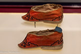 <center>Paire de chaussures de femme pour pieds mutilés</center>Chine XIXe siècle.
Satin coq de roche orné de broderies au passé plat polychromes à motifs floraux, bordure de soie noire.
Don Marie Grobet, 1919. Marseille, Musée Grobet-Labadié, inv. GL 5123.1 et 2.
Cette paire de chaussures chinoises témoigne de la tradition de mutilation des pieds féminins qui apparaît en Chine dès le XIe siècle au sein de l’élite, pour atteindre finalement toutes les couches de la population Han au XIXe siècle.
Il s’agissait d’un rituel consistant à bander les pieds des fillettes âgées de cinq à sept ans, en repliant les orteils sous la voûte plantaire à l’exception du plus gros. L’objectif était de faire en sorte que le pied soit le plus petit possible et prenne la forme d’un bouton de lotus (plein et rond au talon, se terminant en fine pointe à l’avant), ce qui leur valait le nom de « lotus d’or ». Les semelles de soie pouvaient ainsi comporter des décors de broderie revêtant une portée symbolique liée à la fertilité, la longévité, la santé ou le succès. Cette paire présente un motif de fleur de lotus stylisée, métaphore poétique du pied contenu dans le soulier, ainsi qu’une échelle, dont la nature ascendante revêt peut-être une fonction apotropaïque concernant la sphère sociale ou spirituelle.
Contraignant fortement la marche, les pieds mutilés étaient aussi un signe de distinction sociale. Si la pratique du bandage des pieds a été abolie en Chine en 1912, elle disparaît seulement vers 1950.