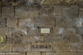 <center>Les Catacombes de Paris. </center> Tout le long du parcours souterrain sont gravées des inscriptions de ce type : 5 J. 1847, signifiant que ce pilier fut le cinquième d’une série exécutée en 1847 sous les ordres de Juncher, Inspecteur général des Carrières de 1842 à 1851. Vous circulez dans des galeries en pierres sèches (hagues) derrières lesquelles se trouvent des bourrages en terre bloquant le haut de la carrière.