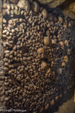 <center>Les Catacombes de Paris. </center> Les ossements, précédemment laissés en vrac, sont soigneusement organisés en murs, sur le modèle des hagues de carriers. En façade, les rangées de tibias alternent avec celles de crânes, tandis que derrière les parements s’entassent les os restants, souvent très fragmentés par les conséquences de leur chute.