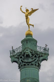 <center>Place de la Bastille.</center>Le sommet est orné d'une sculpture en bronze doré d'Auguste Dumont : le Génie de la Liberté.