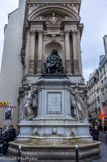 <center>Autour du Palais Royal. </center>La fontaine Molière. Édifiée en 1844, la fontaine est l'œuvre de plusieurs sculpteurs sous la direction de l'architecte Louis Tullius Joachim Visconti et de l'entrepreneur Antoine Vivenel qui réaliseront aussi la fontaine de la place Saint-Sulpice. Au niveau inférieur des mascarons à tête de lion crachent l'eau dans une vasque semi-circulaire.