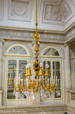 <center>Conseil Constitutionnel.</center> Grand escalier d'honneur. Ce lustre, installé précédemment à l'hôtel de Beauvau, l'actuel ministère de l'intérieur, date du second empire. Composé d'un vase central en acier bleui, de bras et de lampes en bronze doré et de guirlandes en cristal, il se distingue par ses dimensions importantes et son grand nombre de lumières (45).