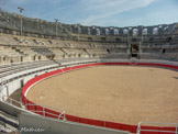 <center>Les arènes. </center> Avec un grand axe de 136 mètres de longueur et un petit axe de 107 mètres, l'amphithéâtre d'Arles est légèrement plus grand que celui de Nîmes et occupe le vingtième rang parmi ceux du monde romain. Le sol de la piste était plus élevé d'environ 2 mètres que le niveau actuel. Il était en effet formé d'un plancher en bois, dont les lames reposaient sur un bourrelet de pierre, au sommet de la partie inférieure du podium. La machinerie nécessaire aux spectacles logeait entre les murs et socles qui assuraient la stabilité de l'arène.
