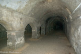 <center>Les cryptoportiques. </center> Les trois galeries dessinent un U ouvert vers l'est, divisées chacune en deux parties par une série de piliers rectangulaires, reliés par des arcs surbaissés. La galerie sud a été creusée dans le rocher.