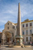 <center>Place de la République. </center> On sait aujourd’hui que l’édifice a été taillé dans le granit d’une carrière romaine d’Asie mineure. De conception monolithique (il fut brisé en deux à la fin de l’Antiquité), il mesure, avec le piédestal conçu par l’architecte arlésien Jacques Peytret, une vingtaine de mètres.