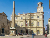 <center>Place de la République. </center> La grande aiguille de pierre, sorte de pivot de la place de la République, provient en fait du cirque romain et date de la fin de l’Antiquité. Découvert au XIVe siècle, ce n’est qu’au XVIIe siècle, que l’obélisque renoue avec sa vocation de symbole solaire. Il fut transporté et installé, avec force difficultés, devant l’hôtel de ville nouvellement édifié,  « pour la plus grande gloire du roi Louis XIV ». Le fût est alors transporté depuis le lieu d'origine, ainsi que la pointe (environ 4 m) depuis la place Antonelle, où elle servait de banc.. Agrémenté d’une fontaine et d’un bassin, il donne la mesure de l’harmonie composée par l’ordonnance des façades aux styles si divers, qui bordent la place.