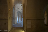 <center>La crypte de Saint Benoit.</center>La crypte, partie basse de l'église abbatiale, est creusée dans le rocher sur son côté sud et construite en pierres de taille dans ses parties nord. Elle rattrape ainsi la déclivité du roc et sert de fondation au monastère. Elle possède une double fonction : fondation de l'abbatiale et église basse. Le déambulatoire est un couloir semi-circulaire haut et étroit dont la voûte assisée en berceau continu aspire le regard grâce à la concavité de son volume courbe à peine distrait par les corbeaux ayant servi à porter les cintres d'échafaudage. Il dessert cinq chapelles rayonnantes.