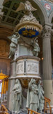 <center>Saint Joseph intra muros. </center> La chaire. Elle est soutenue par trois grandes statues en carton pierre représentant les vertus théologales : la Foi portant un calice, l'Espérance devant une ancre, la Charité tenant un nourrisson et protégeant un enfant.