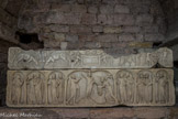 <center>Les travées des cryptes. </center>L'enfeu du sarcophage dit « des compagnes de sainte Ursule ». C'est l'ancienne entrée médiévale de la chapelle Saint-Lazare. Ve siècle, cuve avec son couvercle en bâtière, décor sur une grande face de la cuve et du couvercle, marbre de Carrare. Selon la légende, ce fut à Cologne que ses suivantes furent associées au martyr de la princesse bretonne de retour d'un pèlerinage à Rome. Au centre de la cuve, sous un arc en accolade, se développe la scène de la Traditio legis (don de la Loi à Pierre) tandis que, sous trois arcades réparties sur chacun des côtés, les autres apôtres sont groupés par deux, sauf sous les arcades extrêmes qui n'en abritent qu'un seul. Le Christ se dresse sur la montagne d'où sourdent les Quatre fleuves du Paradis. Il est la colonne manquante du cadre architectural.
En son centre, le couvercle montre deux génies ailés portant une tessère anépigraphe surmontée du chrisme, accosté de deux dauphins. A gauche, deux cerfs, en symétrie, s'abreuvent aux Quatre fleuves du Paradis s'écoulant d'un rocher sur lequel se dresse l'Agneau ; à droite, le miracle de Cana et la grappe de Canaan portée par deux Hébreux, sont une évocation du vin et de l'eau eucharistiques.