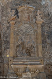 <center>Autel de Saint-Blaise et de Saint-Laurent. XVIIe.</center>Dans le fronton de ce retable baroque on a les armes de la famille d'Hostager. Trois de ses membres seront moine de l'abbaye à la fin du XVIIe et du XVIIIe siècle. Le bas-relief représente Saint-Blaise, évêque et martyre, et Saint-Laurent, diacre. A ses pieds, un ange tient le gril qui fut l'instrument de son martyr. Saint-Blaise, décapité lors de son martyr, est réputé avoir guéri un enfant en retirant de sa gorge une arrête qui l'étouffait. Il est invoqué pour les maux de gorge.