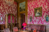 <center>Le château de Champs-sur-Marne. </center>Le Salon Rouge. Cette pièce fut la chambre des épouses des propriétaires, sauf pour Madame de Bourvallais et Suzanne Lévy. Elle fut occupée par Louise Cahen d’Anvers avant que son fils Charles n’en fasse son bureau, après la mort de sa mère. Le décor est marqué par Louise qui en fit sa chambre : elle choisit un lampas rouge, orné de plumes blanches et de dentelles. Son fils Charles fit décaper les boiseries, poser le bandeau à galon d’application sur la partie supérieure et fait peindre la corniche en faux bois.