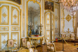 <center>Le château de Chantilly. </center> Le Grand Cabinet d'Angle. Le Grand Cabinet d’Angle était le bureau du prince de Condé, c’est dans cette pièce qu’il recevait ses audiences. Les chaises et les fauteuils de style néoclassique, réalisés par Jean-Baptiste Sené, datent du règne de Louis XVI.  Boiseries à panneaux symétriques mêlant compartiments verticaux et horizontaux, corniches décorées, portes surmontées de peintures – avec fausses portes, si nécessaire, pour préserver la symétrie –, fenêtres ouvrantes à espagnolette, parquets dit « Versailles ». Dessus-de-porte : Choc de cavalerie par Francesco-Giuseppe Casanova (1727-1802).