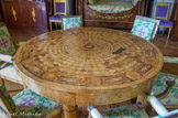 <center>Maisons Laffite.</center> Appartement du maréchal Lannes. Au centre de la pièce, une table de jeu en marqueterie de bois d'orme avec incrustations d'amarante, ayant appartenue à la Duchesse de Berry . Restauration en marquetterie de loupe d'orme et des chaises en bois doré dont quatre sont l'oeuvre de l'ébéniste Jacob.
