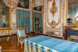 <center>Le cabinet du conseil.</center> Ce n’est qu’en 1755, sous Louis XV, qu’il a pris sa forme actuelle qui résulte de la réunion de deux pièces : le cabinet du Roi où Louis XIV tenait ses conseils et le cabinet des Termes (lieu plus intime où le roi se retrouvait en famille ou en cercle restreint le soir après souper). De somptueuses boiseries, sculptées par Antoine Rousseau sur des dessins de Ange-Jacques Gabriel, ornent ce cabinet de motifs décoratifs illustrant les sujets abordés traités par le roi en son conseil : guerre, justice… La décoration comprend également une pendule de style rocaille (1754), un buste d’Alexandre le Grand en porphyre et deux vases de Mars (sur la photo) et de Minerve, en porcelaine de Sèvres et bronze, ciselés par Pierre-Philippe Thomire (1787). Au-dessus du rideau, Minerve naissant toute armée du cerveau de Jupiter de Houasse, René-Antoine. En plus de la table de conseil dressée avec une nappe en velours, il y a trois fauteuils, douze tabourets pliants et une chaise-longue qu’utilisa Louis XIV en 1686 lors de la crise de la fistule anale