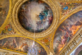 <center> Le salon de la Paix.</center> La France est peinte au centre de la voûte, assise au milieu des nuées, derrière elle, la Gloire ; son char est tiré par quatre colombes ; celles-ci symbolisent les mariages de Marie-Louise d’Orléans, fille de Monsieur, frère de Louis XIV, avec le roi d’Espagne Charles II (1679) et du Dauphin, fils de Louis XIV, avec Marie Anne Christine Victoire de Bavière (1680). Deux autres colombes sont peintes tout en bas de la composition : elles symbolisent le mariage du duc de Savoie, Victor Amédée II, avec Anne-Marie d’Orléans, autre fille de Philippe d’Orléans, frère de Louis XIV (1684). Ces mariages ont en effet suivi les traités de Nimègue et ils marquent la paix retrouvée des puissances européennes. La France ordonne par ailleurs à Mercure d’aller porter la paix en Europe, ce qui est symbolisé par les putti apportant des branches d’olivier à l’Allemagne, à l’Espagne et à la Hollande, peintes dans les voussures du plafond. Voussure du bas : L’Espagne est l’une des puissances alliées que la France a combattues lors de la guerre de Hollande (1672-1678). Elle s’apprête ici à recevoir le rameau d’olivier, symbole de paix, des mains d’un putto envoyé par l’allégorie de la France, peinte dans la coupole. Un feu d’artifice est représenté à l’arrière-plan. Le peuple espagnol en liesse danse et joue de la musique à droite, tandis que des putti brûlent des armes dans la partie gauche de la composition. A droite, l’Europe chrétienne est représentée au centre de la composition, portant une corne d’abondance symbolisant la prospérité, fruit du retour de la paix. Sur le bouclier à ses pieds, le turban et le croissant turc signifient que la menace ottomane est désormais écartée. La Piété est peinte à droite de l’Europe et la Justice, accompagnée d’Amours symbolisant les arts, à gauche.