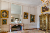 <center>Seconde antichambre de la Dauphine.</center> Divisée à l’origine en quatre pièces, cette salle fit partie, jusqu’en 1693, de l’appartement de la duchesse de Montpensier. Elle devint ensuite le vestibule de l’appartement du Grand Dauphin, puis de son fils aîné le duc de Bourgogne. Antichambre du duc de Berry de 1712 à 1714, elle fit ensuite partie de l’appartement du maréchal de Villars et devint enfin, en 1747, la seconde antichambre de la Dauphine. Deux tableaux de fleurs peints par Blain de Fontenay sont accrochés au dessus des portes. Sur la belle cheminée de marbre, est disposé un buste sculpté  du  Régent.  Le  régent  est  la  personne  qui exerce la charge du Roi quand il est trop jeune ou incapable de remplir ses obligations.