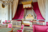 <center> Le Grand Trianon.</center> La chambre de l’Impératrice. Ancienne chambre de Louis XIV, elle a conservé son décor caractérisé par la présence de colonnes corinthiennes partageant la pièce en deux espaces distincts et par l’admirable qualité de ses boiseries. Sous l’Empire, elle fut divisée pour former une chambre plus petite et un salon (ou antichambre) qui servit à l’impératrice Marie-Louise qui le remeubla dans son état actuel ; le seul meuble qui fait exception est le lit, qui fut celui de Napoléon aux Tuileries et dans lequel mourut Louis XVIII, frère de Louis XVI, en 1824.