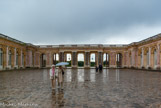 <center> Le Grand Trianon.</center> Dessiné par Jules Hardouin-Mansart suivant les ordres de Louis XIV, et construit sous la supervision de Robert de Cotte et du roi lui-mêmen, le Grand Trianon est de style classique français mêlé d’italianismeNote, à dominante rose. L’appartement des souveraines dans l’aile gauche est relié aux appartements des souverains dans l’aile droite par le Péristyle. L’ensemble est couvert d’un toit plat masqué par une balustrade. Les murs sont en une pierre blonde, la pierre de Saint-Leu. Contre les arcades du péristyle du côté de la cour, huit colonnes non porteuses de marbre de Campan, sont groupées deux par deux.