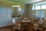 <center> Le Petit Trianon.</center> Boudoir. Cette petite pièce de l'angle nord-est du château n'est à l'origine destinée qu'à permettre le passage entre le rez-de-chaussée et les appartements privés du Roi situés en entresol ou en attique. En 1776, Marie-Antoinette fait transformer l'endroit en boudoir. On installe un mécanisme ingénieux permettant d'obturer par de grands miroirs s'élevant du sol les deux fenêtres de cette piècec, qui est directement accessible depuis le perron est donnant sur le jardin fleuriste de Louis XV, futur jardin anglo-chinois. La mécanique est installée à l'étage inférieur sous la direction de l'ingénieur des Menus-Plaisirs, Jean-Tobie Mercklein. En 1787, Marie-Antoinette demande à son architecte Mique de redessiner la décoration de cette pièce, bien que jusque-là « élégamment décorée ». Les frères Jules-Hugues et Jean-Siméon Rousseau réalisent des lambris richement ouvragés dans un style arabesque : les sculptures se détachent en blanc sur un fond peint de bleu, à la manière des camées de Wedgwood, marque du nouveau goût de la France pour l'anglomanie.