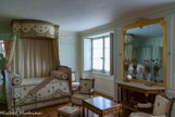 <center> Le Petit Trianon.</center> Chambre de la Reine. Cette pièce, de même que le boudoir et le cabinet de toilette voisins, possède un plafond abaissé, permettant de créer le niveau supérieur d'entresol, ce qui accentue la sensation d'intimité. C'est le cabinet de retraite du roi Louis XV. Comme dans les autres pièces, Guibert réalise la décoration sculptée des boiseries, sur le thème des plantes, mêlant paniers et festons surplombés de coquilles. En 1772, la pièce est transformée en chambre pour madame du Barry, qui occupe jusque-là un appartement dans l'attique. En investissant le château, Marie-Antoinette fait sienne cette chambre. Elle commande en 1787 un nouveau mobilier, probablement dessiné par Jean Démosthène- Dugoure.