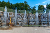 <center>Les jardins de Versailles.</center> Bosquet de la Salle de Bal. Le Nôtre utilisa habilement l’importante déclivité provoquée par les rampes du parterre de Latone pour concevoir une grande cascade – la seule de Versailles – qui occupe tout le côté oriental de l’amphithéâtre. Cette cascade à huit degrés est scandée de rampes de marbre. L’ensemble a reçu un décor de pierres de meulière et de coquillages, auquel s’ajoutent de grands guéridons et des vases de plomb doré.