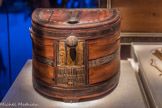 Boîte et couvercle en demi-lune en bois rouge avec incrustations d’ébène et d’ivoire et cartouches de Toutânkhamon.
Les cartouches de Toutânkhamon et d Ànkhésenamon figurent sur le devant de la boîte. Juste au-dessous, se trouve le sema-taouy, symbole de l'unité de la Haute-Égypte et de la Basse-Égypte.
Boite et couvercle : Ébène, bois rouge, feuille d’or, bronze.