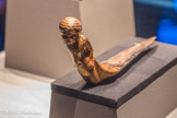 Figurine en bois doré d’un prisonnier sur une pièce de bois courbée en forme de pointe de dague.
Les bras entravés de chaque côté, le prisonnier n’a aucun moyen de s'échapper. Cet élément d'un char célèbre le triomphe de Toutânkhamon sur ses ennemis.
Bois, gesso, feuille d'or