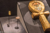 Bague en or gravée d'une barque solaire et sertie de deux babouins en adoration.
La pleine lune et le croissant de lune prennent place dans une barque lunaire avec deux babouins. La lune et les babouins représentent Thot, dieu de la sagesse et de la guérison.
Or. <br>
Boitier à miroir en forme d’ânkh en bois doré incrusté de verre bleu et de cornaline
Les miroirs symbolisaient la résurrection et la vie éternelle. Les croix ansées, ou ânkh, représenta la vie. Ici, le disque solaire et des scarabées en cornaline encadrent le nom de Toutânkhamon.
Bois, feuille d'or, verre, cornaline.