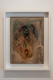 <center>Abbaye de Beaulieu-en-Rouergue  </center>Henri Michaux (Namur, 1899 - Paris, 1984)
Tête tragique.
1954-1955
Huile sur carton.
Michaux peint à l'huile dès 1926. Cependant, il cherche sans cesse à gagner en souplesse et en vitesse d'exécution. S'accommodant mal du temps de séchage de t'huile et de son caractère pâteux, il lui préfère l'encre de Chine, l'aquarelle, la gouache et, plus tard, l'acrylique. Pourtant, l'huile revient régulièrement dans sa production, comme Illustre cette œuvre, surnommée Tête tragique par Geneviève Bonnefoi. S'inscrivant dans la lignée des têtes à l'aquarelle de 1946-48, elle sera suivie de la période mescalinienne.