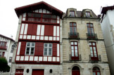 <center>Alexandrenia et la Maison des Trois canons</center>Ces deux maisons sont caractéristiques de l'architecture de Saint-Jean-de-Luz des XVIIe et XVIIe siècles.
Si elles possèdent les mêmes dimensions de parcelle et une façade orientée vers l'est, tournant le dos au mauvais temps qui vient de la mer, la maison labourdine obéit à une logique régionale tandis que la maison bourgeoise répond à une logique économique.
Alexandrenia est la transposition urbaine de l'Etxe, la ferme traditionnelle labourdine.
Construite au XVI ou XVIIe siècle sur le parcellaire médiéval elle présente une façade en pignon et un faîtage perpendiculaire à la rue, permettant l'écoulement des eaux de pluie le long des murs gouttereaux.
Elle est transformée en 1690 comme en atteste la poutre ouvragée du premier niveau. La belle porte d'entrée et les deux œil-de-bœuf datent aussi de cette époque.
La façade est constituée d'un maillage de pans de bois ou colombages, chaque étage venant en encorbellement sur le précèdent. Les avancées reposent sur des abouts de solives sculptées.
Au début du XXe siècle, la toiture est surélevée pour créer un quatrième niveau avec loggia.
La couleur traditionnelle des bois, rouge basque, viendrait du sang de bœuf utilisé à l'époque comme teinture.