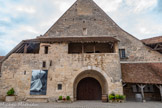 <center>Le Clos Vougeot</center>Grand cellier et dortoir des moines vus de la cour intérieure. Cette grande salle construite en 1170 est l'ancien cellier des moines. La porte nord permettait l’entrée des charrettes dans les cinq travées de la nef centrale et autorisait le roulage des tonneaux jusque dans les nefs latérales. Les murs épais, les fenêtres étroites et le plafond isolé maintenaient une température stable, favorisant l’élevage des vins en pièces bourguignonnes (fûts de chêne de 228 litres). Les dalles en pierre de Bourgogne ont remplacé la terre battue d’autrefois.