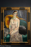 Femme aux bijoux. KEES VAN DONGEN, (1877-1968). Huile sur toile, 1929.
II s'agit avec Femme aux bijoux d'un magnifique exemple de l'art de Van Dongen dans les années 1920. Une jeune femme non identifiée dont l'apparence saisissante, la robe précieuse et les bijoux, loi donne éclat et audace, arbore les caractéristiques typiques des portraits les plus glamours de l'artiste.
Vêtue d'une robe de soirée élégante, sa beauté est accentuée par la brillance de sa chevelure et par les étincelants colliers et bracelets qu'elle porte et qui sont peints à l'aide d'empâtements. Les attributs, dont la fourrure posée sur le bord du canapé, laissent à penser qu'il s'agit d'une femme de la haute société, même si le peintre s'attarde plus à la féminité du modèle qu'à son identité. Le traitement subtil de sa chair et le reflet argenté de sa robe sont sublimés par le contraste avec le vert profond du canapé et de l'alcôve sombre de l'arrière-plan. Les reflets verts sur la peau du modèle montrent à quel point te peintre se soucie peu d'anatomie ou de représentation naturaliste mais privilégie la présence physique et sensuelle du modèle. Ils sont par ailleurs les derniers témoins éblouissants de la période fauve du peintre dont le point d'orgue se situe entre 1901 et 1914.
