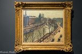 La Seine, quai des grands Augustins. ALBERT MARQUET (1875-1947). Huile sur toile.
 
Proche d’Henri Matisse, son ancien camarade de l’atelier Gustave Moreau, Marquet qui était présent à ses côtés dans la fameuse « Cage aux fauves » du salon d’automne de 1905, fut dès lors assimilé au fauvisme. C’est pourtant dans l’art des gris, et non dans les outrances de la couleur, que Marquet trouva son mode d’expression. Son art est celui de la synthèse : Marquet d’un trait de pinceau noir, donne l’essence du mouvement et de l’atmosphère.
Tout comme Matisse fut un grand maître de la surface par le décoratif, Marquet excella dans la peinture de l’étendue, celle du plan d’eau, du port d’Alger où il vécut longtemps, de Marseille, d’Arcachon ou de la Seine, à la Frette ou à Paris. D’abord installé à Paris quai Saint-Michel, puis en 1931 dans l’atelier du 1 rue Dauphine, à l’angle du quai des Grands-Augustins, il peint la Seine et ses quais. La vue du cinquième étage de la rue Dauphine lui permet de déployer l’espace de part et d’autre du bras du fleuve qui longe l’île de la Cité en faisant un coude. À droite, sur le quai bordé d’arbre, quelques passants et de rares automobiles animent cette belle matinée de fin d’automne. En face, Quai des Orfèvres, se détachent la silhouette de l’hôtel de Police et au loin, fantomatiques, celles du Pont-Saint-Michel et de Notre-Dame. La lumière froide est déjà pas pâle, les arbres dépouillés de leurs feuilles, tout évoque dans cette vue l’hiver qui s’approche.