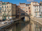 <center> Pont des Marchands</center> Son origine remonte à l'époque romaine. Il franchit le canal de la Robine et a la particularité d'être un des rares ponts encore habités de France.