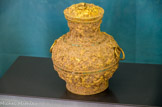 <center>Le jade</center>Vase couvert.
(Dynastie des Han de l’Est, 25 — 220).
Or, incrustations de turquoises
Ce vase couvert de type zhong, orné de motifs de dragons sans cornes, est destiné à contenir des boissons, des alcools, lors de cérémonies rituelles ; cette forme se rencontre dès la dynastie des Shang (XVIIe- XIe siècle avant notre ère). Cette pièce et son pendant ont été réalisés en l’an 48, comme l’atteste l’inscription sous la base.