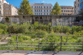 <center>Place de la Bourse </center> Elle se compose d'une fine nef supportée par une structure métallique. Un rideau d'eau naissant à la limite du pont et de la coque s'écoule dans un bassin orné de la devise de Marseille, qui est cachée par la végétation,  «Actibus immenses urbs fulget Massiliensis» : La Ville de Marseille brille par ses hauts faits.