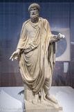 <center>Statue du magistrat au nom de Caninius</center>Le procurateur Caninius administrait la province d'Afrique au nom de l'empereur dont il dépendait directement. Il est représenté vêtu de la toge cérémonielle des magistrats, grande pièce de laine au drapé codifié, qui était à l'origine l'insigne des citoyens romains. Marbre.
