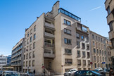 <center>Rue Henri Cheneau </center>Bentz Y, Devin A. architectes 1952. Cet immeuble à tous les traits de ceux réalisés par ces architectes, qui multiplient les prises d'angle dans le quartier de Perler. Naturellement l'entrée est dans l'angle, sur un glissement de plan, avec un porche sous une dalle de balcon en léger débord. De part et d'autre, des percements en travées régulières. Ici, une terrasse est soulignée par un cadre excédant la façade, là, des souches de ventilation s'inscrivent dans le dispositif perspectif, à la manière de Sauvage ou de Sant'Elia. L'ensemble est paré de pierres clairclaires dont les plans sont soulignés par les pièces de couvrement : têtes de murs, appui de baies.