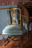 La chambre de Pauline de Caumont.<br>Cette paire de chaises à entretoise en bois laqué rouge et or est ornée d'un décor sinisant. Véritable mélange de cultures, ces objets permettent de voir un répertoire décoratif hérité de l'orient sur des objets typiquement européens.
Depuis le 18e siècle et la naissance de la compagnie des Indes orientales, l'Europe est friande d'objets venant d'Asie ou d'inspiration asiatique dans sa décoration. En parallèle des nombreuses importations de laques et de porcelaines chinoises, nait une production européenne d'objets vernis à l'imitation de la laque. Cela permet de faire baisser les coûts mais aussi de s'adapter plus facilement aux goûts de la clientèle européenne ; cette paire de chaises en est l'exemple typique.