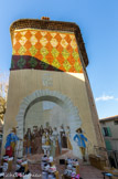 <center>Carcès.</center> Façade couverte d'écailles en faïence de Salernes. Fresque : arrivée de Louis XIV à Carcès. On reconnait la plorte.