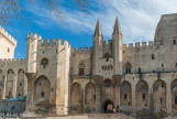 Le Palais des papes vue de la Place du Palais. La construction du palais des Papes s'effectue en moins de 20 ans, de 1335 à 1352. Elle est l'œuvre principalement de deux papes bâtisseurs : Benoît XII, qui fait construire le premier palais pontifical (dit Palais vieux), et Clément VI, qui fait édifier de nouvelles extensions (dit Palais neuf). Benoît XII, confie la direction du chantier à son compatriote du comté de Foix, l’architecte Pierre Poisson. Dès le début de son pontificat, Clément VI achève la tour de Trouillas, ajoute une nouvelle tour des cuisines et fait construire la Tour de la Garde-Robe, accolée à la Tour du Pape.

Par la suite, l’architecte  Jean de Louvres, originaire de l’Ile-de-France, acquiert le statut de maître des œuvres et supervise toute l’organisation du chantier des nouvelles extensions, qui mobilisera en moyenne 600 hommes dans un contexte pourtant troublé par la guerre de Cent Ans et la peste noire.