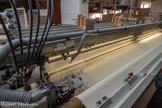 <center>La manufacture Brun de Vian-Tiran.</center>Entre les fils de chaîne va passer un autre fil, dit de trame. Auparavant, c’étaient des navettes en bois qui passaient d’un côté et de l’autre du métier. Maintenant, ce sont des pinces qui emmènent le fil sur toute la largeur du métier, ou sur la moitié, deux pinces se passant le fil de trame au milieu. Ces pinces se déplavent à 300 km/h. Un peigne (la tige métallique)  va tasser le fil de trame sur le tissu. Puis les cadres vont changer de place et s’inverser du haut vers le bas. Un autre fil de trame passe, le peigne tasse et ainsi de suite : le tissage va continuer ainsi pendant des centaines de mètres. Au premier plan, le produit tissé.