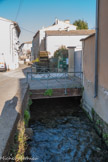 <center>La rue des Roues</center>Les rues Théophile Jean et du Docteur Roux, plus connues sous le nom de « rue des Roues », nous font découvrir l’histoire hospitalière et industrielle de L’Isle-sur-la-Sorgue. L’énergie hydraulique est très probablement à l’origine du développement de L’Isle-sur-la-Sorgue dès le XIe siècle. Aux XIIe et XIIIe siècles, c’est une ville drapière d’importance, dont les produits sont exportés sur les foires et par le port de Marseille. Les roues permettaient aux moulins à foulon de battre les draps de laine afin de les assouplir et les dégraisser. À la fin du Moyen Age, il existait aussi des moulins à céréales et à papeterie.