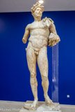 <center>Le musée.</center>Hadrien (né en 76 à Italico. Espagne. Empereur de 117à 138) était un homme de lettre épris de philosophie et d'éloquence qui parlait aussi bien grec que latin. Il a régné plus de 20 ans, perfectionnant l'administration et sécurisant les frontières de l'empire. Des caractéristiques helléniques se retrouvent dans cette sculpture en ronde-bosse d'une grande qualité de modelée : la barbe à la manière des philosophes grecs, la nudité. La couronne végétale à médaillon axial et le manteau impérial sur l'épaule gauche marquent la dignité impériale.